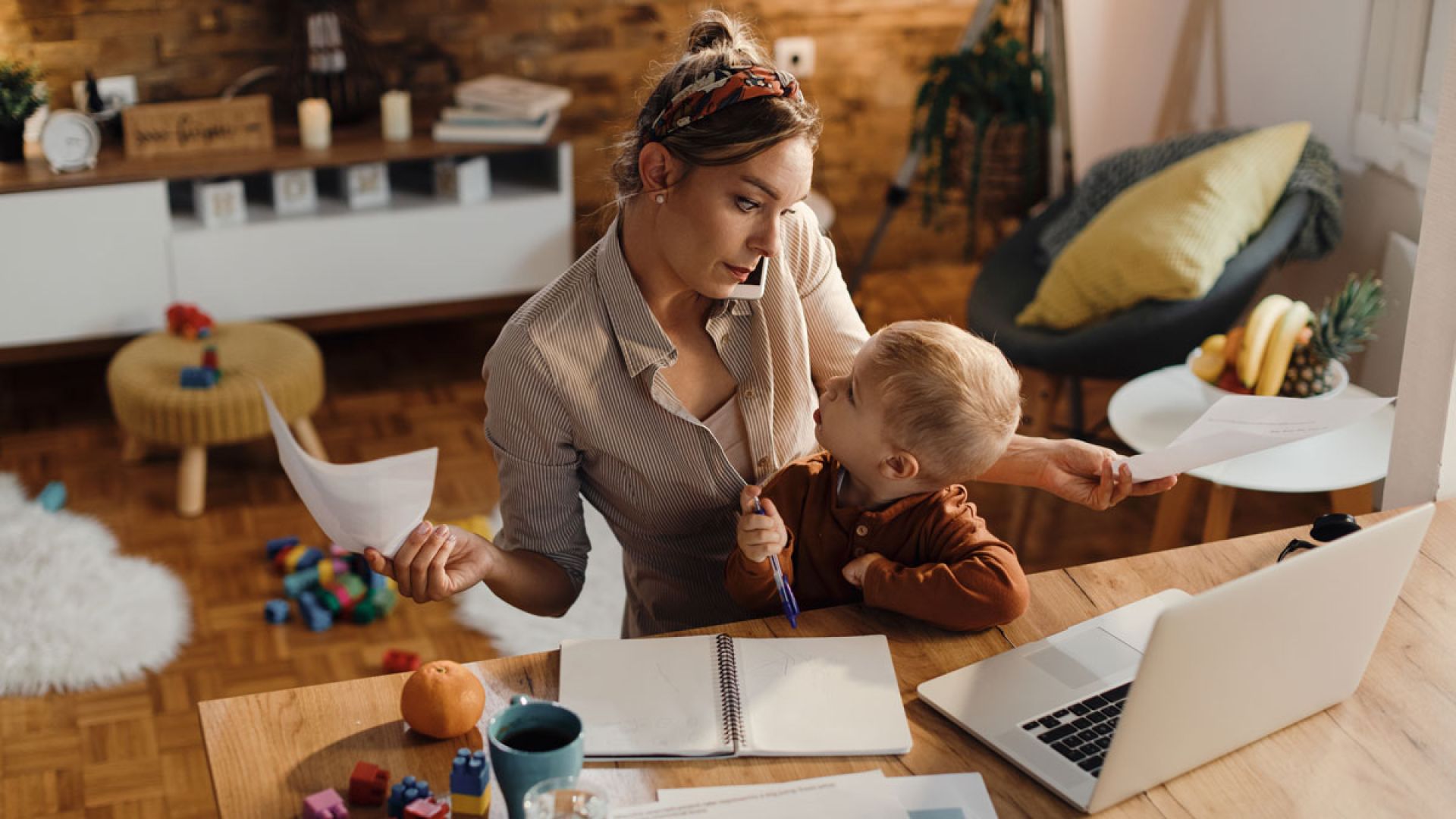 busy mom working at home with toddler in lap